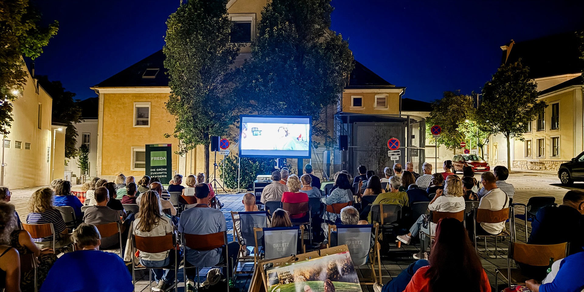 Open-Air-Kino in Österreich: Publikum blickt auf Leinwand vor Gebäuden bei Nacht